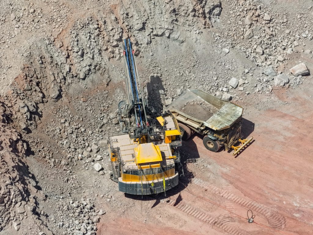 Material extraction and loading process with heavy machinery in an open pit mine