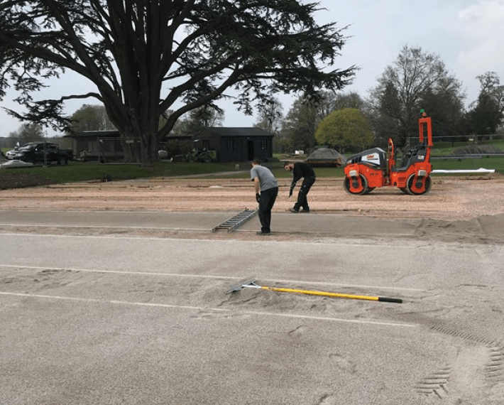 construction of cricket nets with two men working and a roller