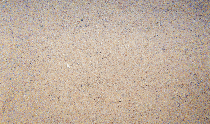Sub-angular particles of kiln dried sand with varied colours, displayed loose.
