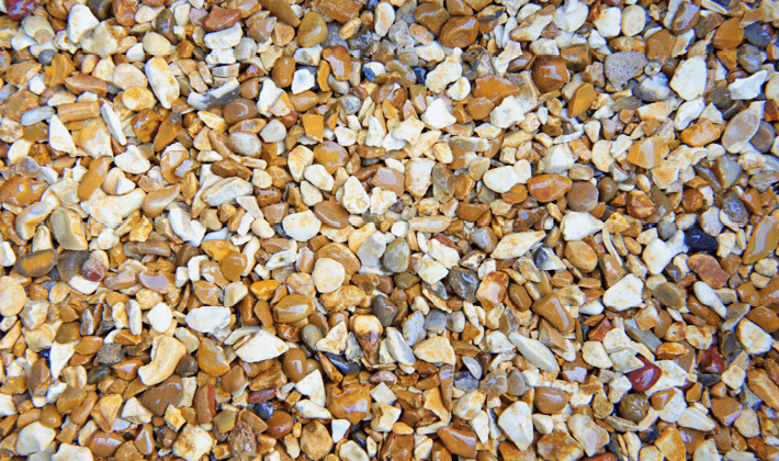 Loose shingle with golden, brown and white flint faces, containing grades from 4mm to 10mm, displayed wet.