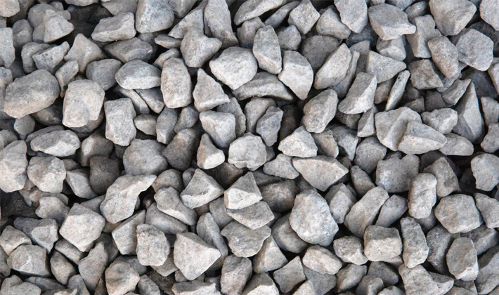 Loose display of black basalt, showcasing dark grey angular stones graded from 10mm to 20mm, presented in a dry condition.